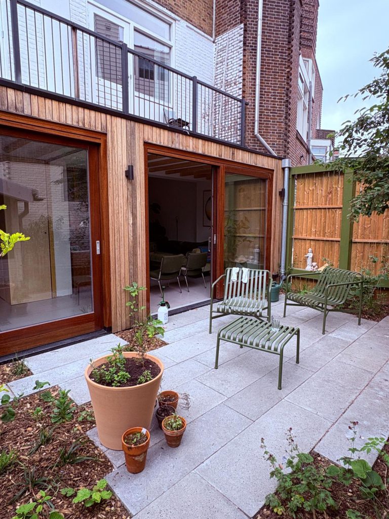 Moderne aanbouw met houten gevelbekleding en houten schuifdeuren. 